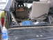1974 Ford Bronco - The interior of a 1974 Ford Bronco shows its seats, a blue coiled hose, and a metal bracket in the cargo area.