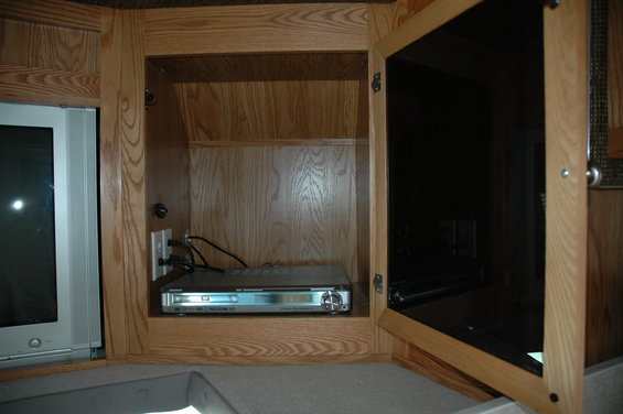 RV entertainment cabinet with wooden doors, a DVD player, and a television