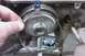 2005 GMC Yukon - A hand holds a metal ring near a component of a vehicle's transmission system.