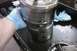 2005 GMC Yukon - A mechanic's gloved hand holds a metal part, possibly from a transmission, with a blue shop towel in the background.