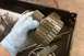 2005 GMC Yukon - A gloved hand holds a set of transmission gears over a toolbox containing other parts and tools.