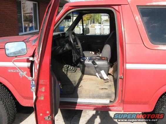 1981 Ford Bronco interior with driver's door open, showing seats, steering wheel, and floor