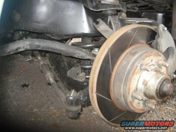 Close-up of a vehicle's front suspension with brake rotor and hub visible