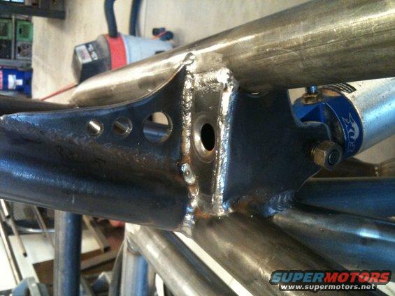 Close-up of welded metal tubing and suspension components on a custom buggy frame. Features a blue Fox shock absorber