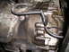 1997 Ford F-250 - Close-up view of a greasy transmission housing with visible oil leaks and a metal identification tag.