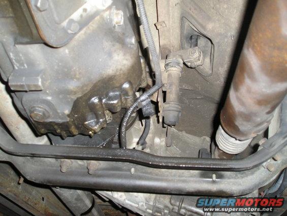 Underside view of a vehicle's transmission and exhaust system, showing some leaks