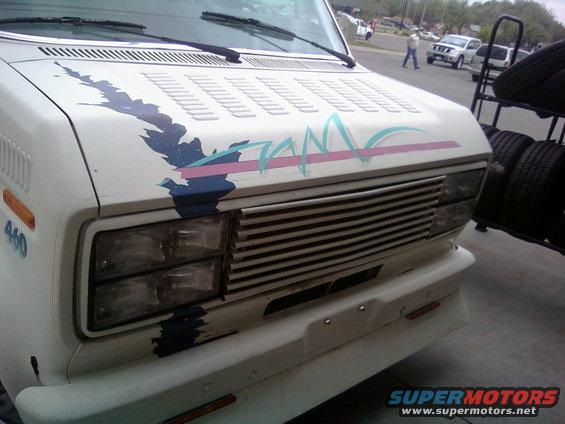 Front view of a white van with a blue, pink, and teal graphic on the hood. "460" is visible on the side