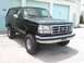 1995 Ford Bronco - This black Ford Bronco is parked in front of a row of garage doors.
