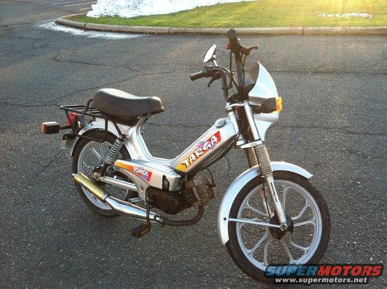Silver Tomos Targa moped parked on asphalt with grass and snow in background