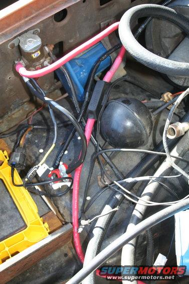 Engine bay wiring with pink and black cables, blue capacitor, and black spherical component