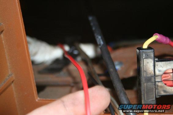Close-up of vehicle wiring harness with red and yellow wires connected to a black connector