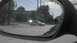 1989 Ford Bronco - A silver sedan is captured in the side mirror as it makes a turn at an intersection on a sunny day.