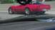 1989 Ford Bronco - A red sports car drives on the highway, seen from behind.