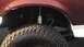 1989 Ford Bronco - This image focuses on the tire and suspension system of a vehicle, with a portion of the maroon-colored body visible.