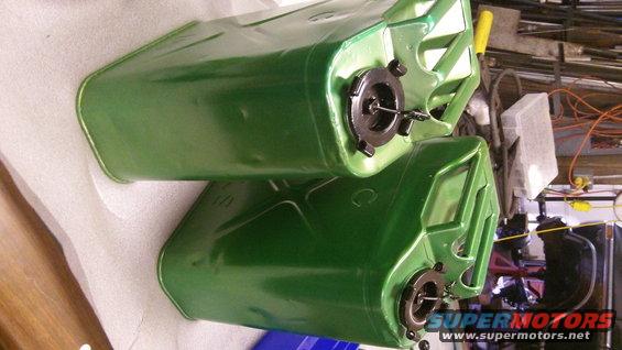 Two green jerry cans stacked, one on top of the other. They have black caps with spouts