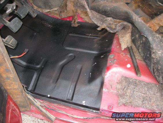Black metal floor panel with red metal framing and brown insulation visible