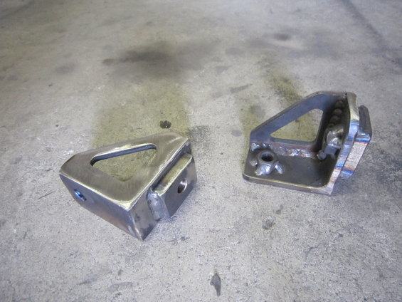 Two metal winch mounting brackets on a concrete surface