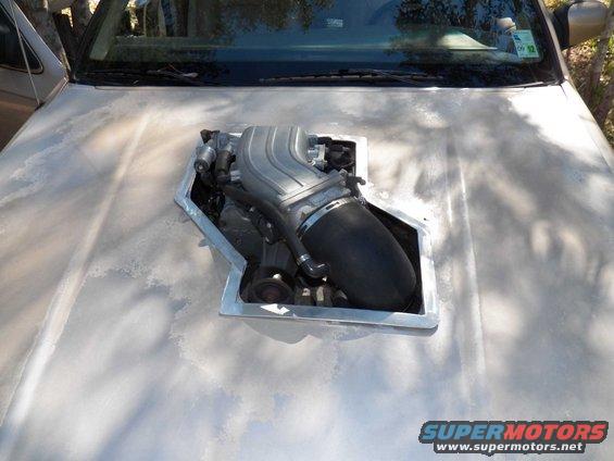 Engine intake manifold installed in a cutout on a car's hood