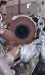 Close-up of a rusty exhaust pipe and catalytic converter assembly hanging from chains