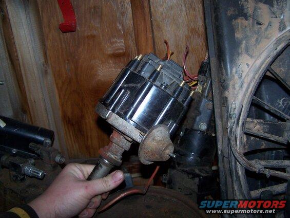 Hand holding a car distributor with wires connected