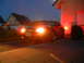 2003 Mercury Marauder - A red coupe is parked in front of a house at dusk, with its headlights illuminated.