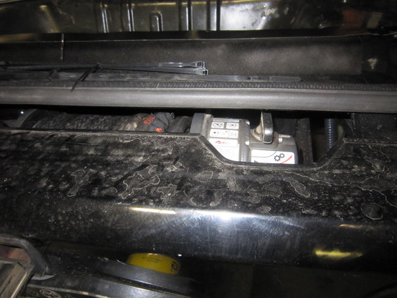 Winch with warning symbols and a lever, mounted behind a dirty black bumper
