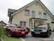 2003 Mercury Marauder - A red Ford Mustang and a black Audi A6 are parked in front of a modern house. The Audi's license plate indicates it is a 2006 model.
