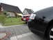 2003 Mercury Marauder - A red Ford Mustang is parked in a driveway next to a black car, with houses in the background.