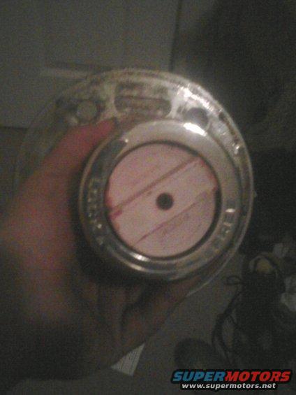 Chrome hubcap with a pink center and black bolt hole, held by a hand