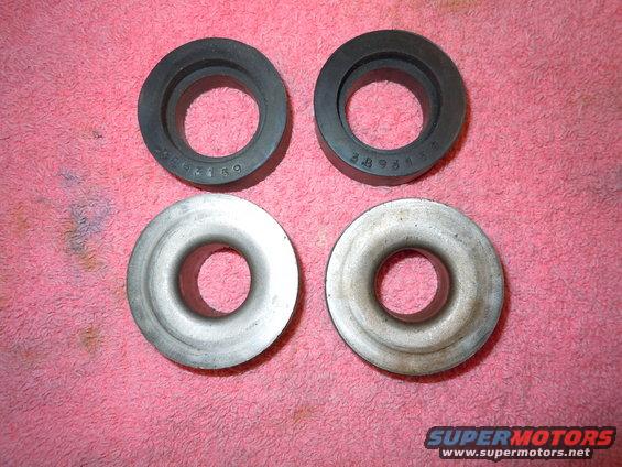 Four automotive rings, two black rubber and two silver metal, arranged in a two-by-two grid on a pink cloth