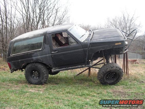 Black lifted SUV with roll cage and large tires, side view