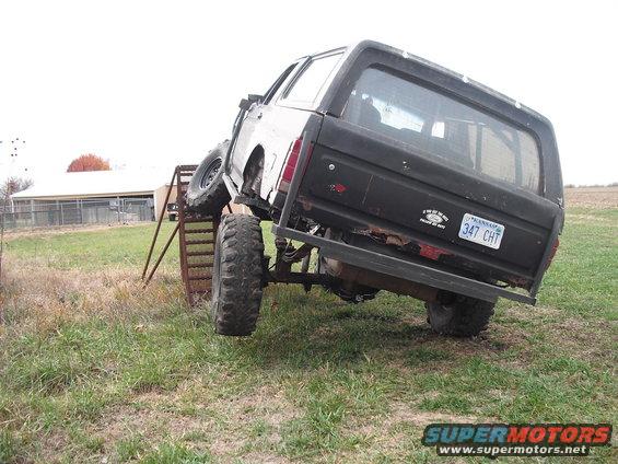 1986 Ford Bronco rear view, angled on a metal ramp with large tires