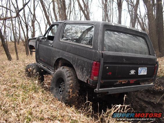 Black Ford Bronco with lifted suspension and large tires stuck in mud off-road