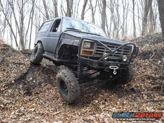 Modified Ford Bronco with custom bumper and lift kit climbing a dirt hill