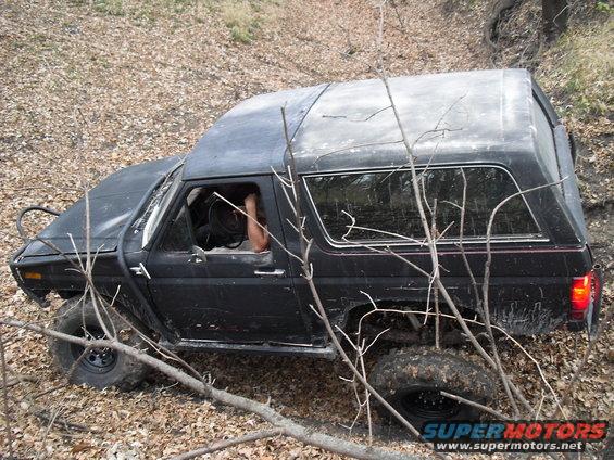Black Ford Bronco off-roading on a dirt path with trees and leaves