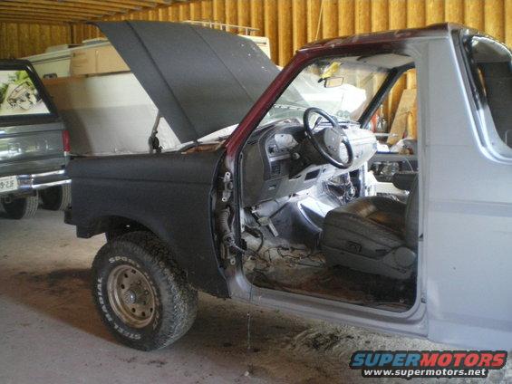 1988 Ford Bronco interior and front fender disassembled, hood open, in a garage