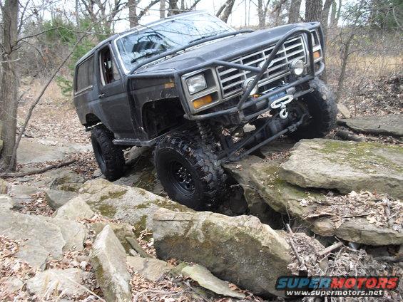 Black 1986 Ford Bronco off-roading over rocks
