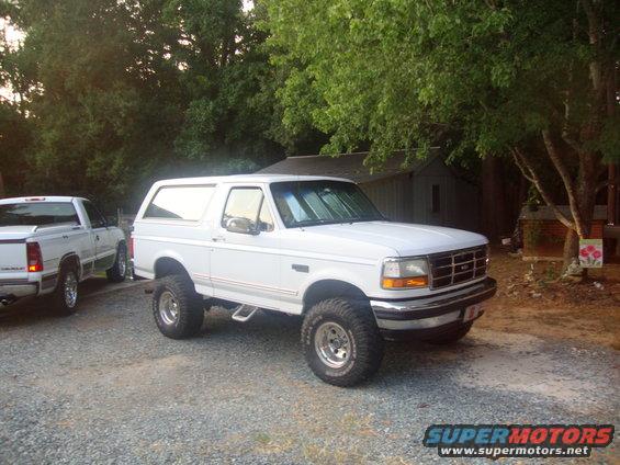 White 1995 Ford Bronco parked on gravel, another white truck to the left
