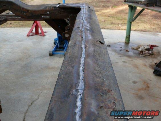 Welded vehicle frame section on jack stands and a blue floor jack