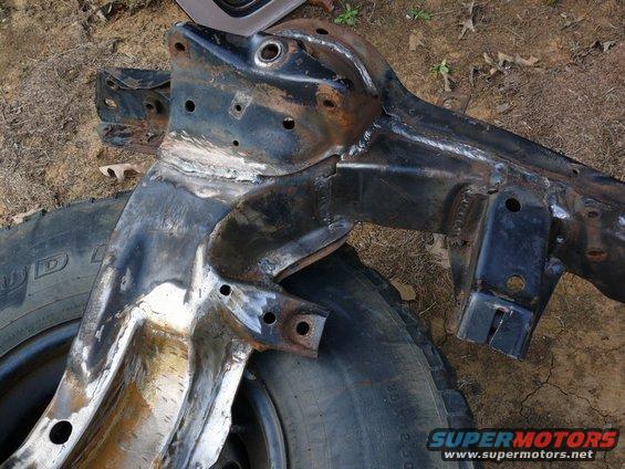 Rusty car frame with visible welds and a tire underneath