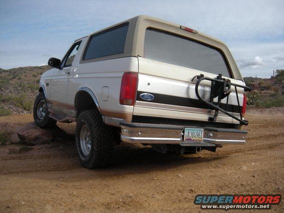 1995 Ford Bronco parked on dirt with a spare tire carrier on the back