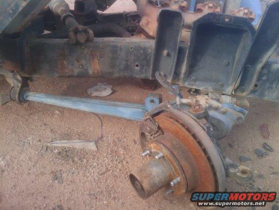 rusted vehicle frame with front suspension components, including brake rotor and hub