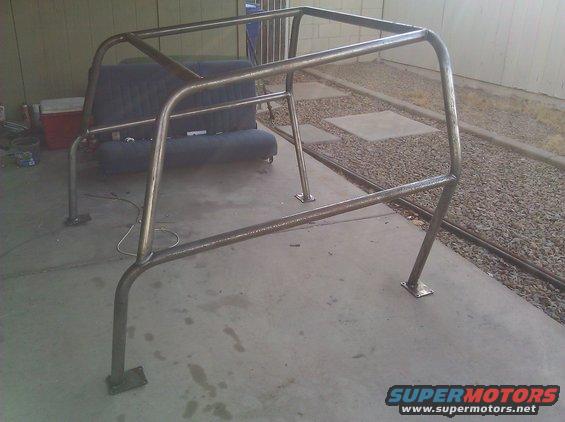 Metal roll cage frame sitting on concrete, with a couch in the background