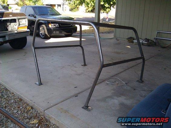 Roll cage in front of a black SUV and a brown Ford Bronco