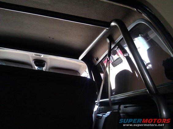 Interior view of a vehicle's roll cage and headliner, with a seatbelt visible