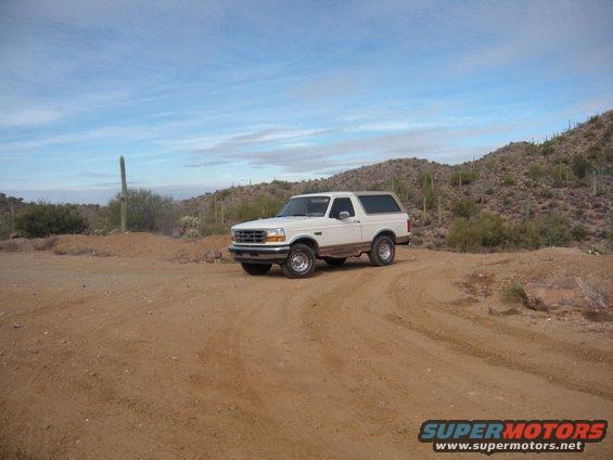 1995 Ford Bronco, 3q-front view, white with brown trim, parked on dirt road in desert
