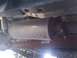 2008 Nissan Titan - The underside of a vehicle reveals an exhaust system component with embossed text and a driveshaft.
