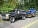 1978 Ford Bronco - A black 1978 Ford Bronco is seen from the front-three-quarter view, towing a blue off-road buggy on a trailer.