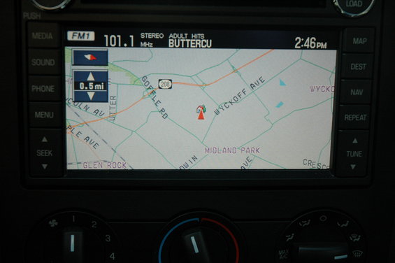 Car's navigation screen showing map with streets like Gofle Rd and Wyckoff Ave, plus radio info