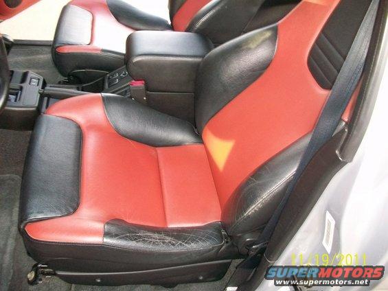 Front seats with red and black leather upholstery, center console, and seatbelt